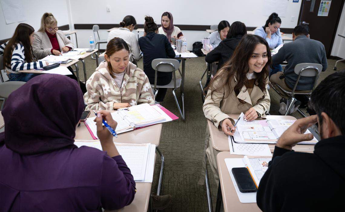 Students Maria Quijano, left, and Laili Ahmadi, right, work with classmates during a English language class for nursing assistant students.