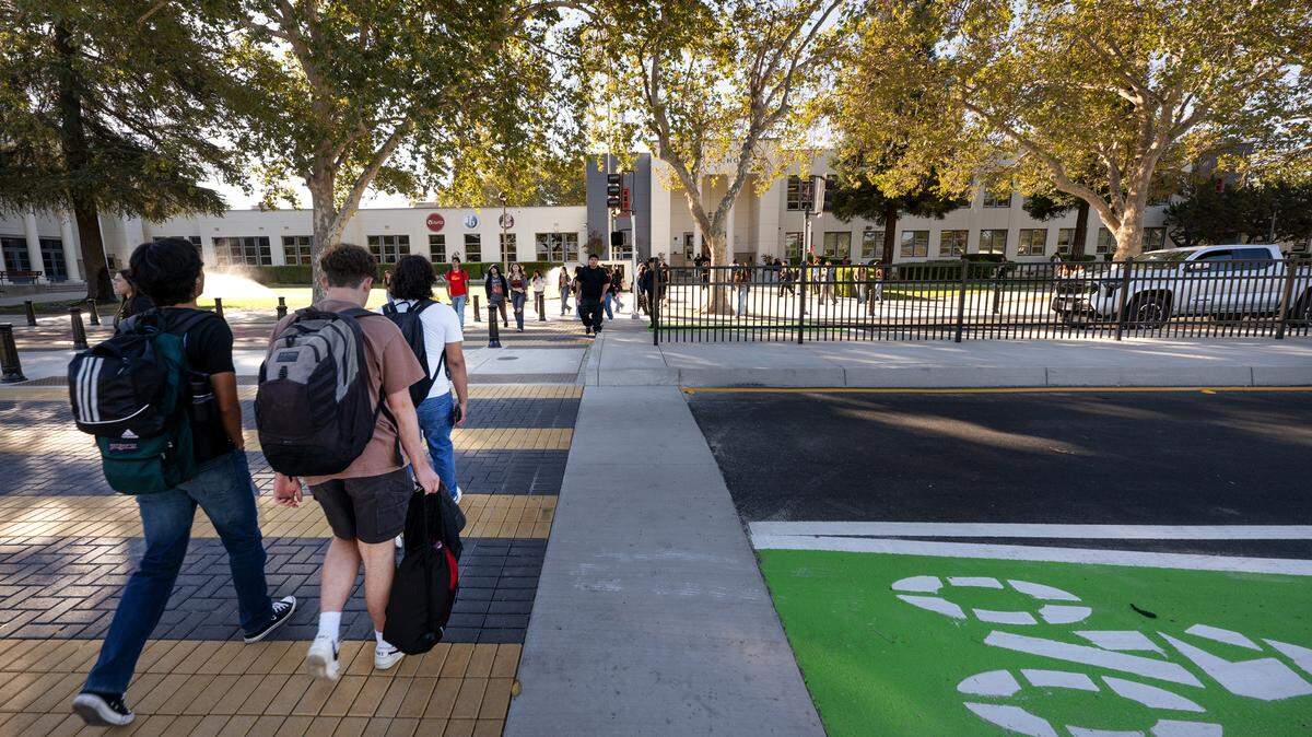 Students cross Paradise Road outside Modesto High School in Modesto, Calif., Tuesday, Aug. 20, 2024. In an effort to improve safety the city recently reduced vehicle traffic to two lanes added bicycle lanes and improved the crosswalks around the school.