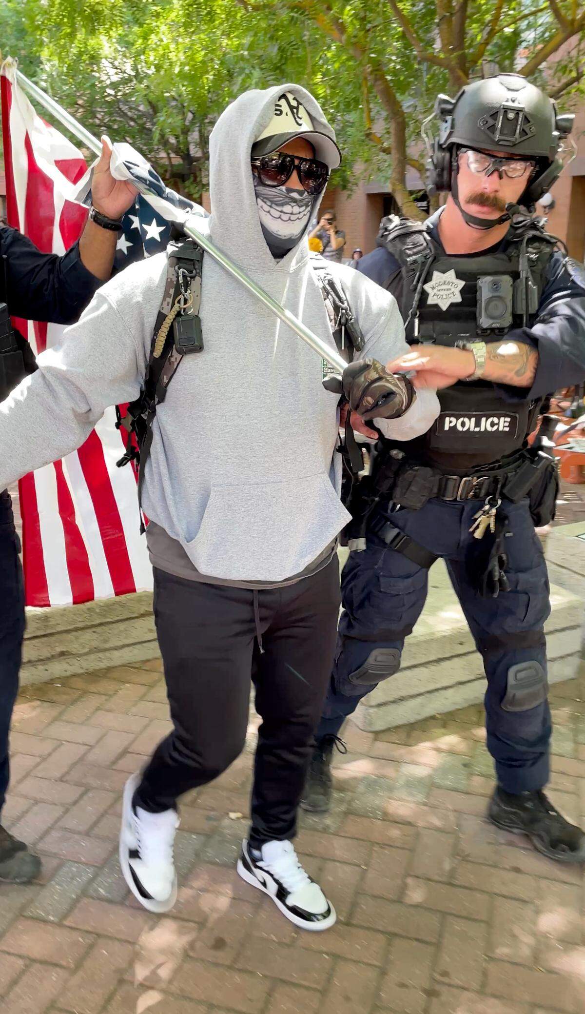 A protester is detained by Modesto police during a rally at 10th Street Plaza in Modesto, Saturday, June 14, 2025.