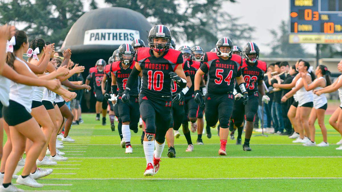 The Modesto High Football team runs onto the field before a football game between Modesto High School and Johansen High School at Downey High School in Modesto California on August 20, 2021.