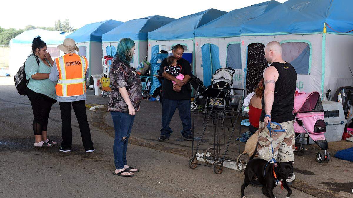 LVN Hortencia Maldonado, with Golden Valley Health Centers at far left works with homeless people in April at the Modesto Outdoor Emergency Shelter in Modesto, Calif.