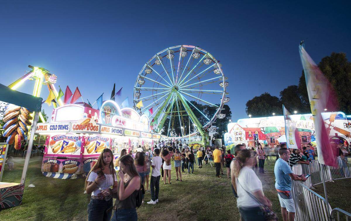 People are pictured on the midway on opening day at the Stanislaus County Fair in Turlock, Calif., Friday, July 12, 2019.