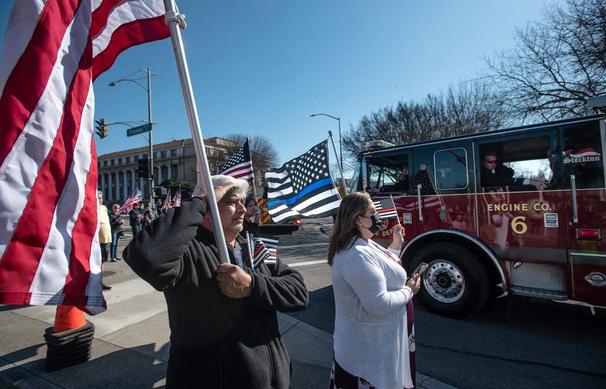 Daniel Gray, left, salutes as the final procession of firefighters follow the body of fallen Stockton Fire Capt. Vidal “Max” Fortuna as he is transported to his burial site after a memorial service at the Banner Island Ballpark in Stockton, Calif., on Tuesday, Feb. 8, 2022.