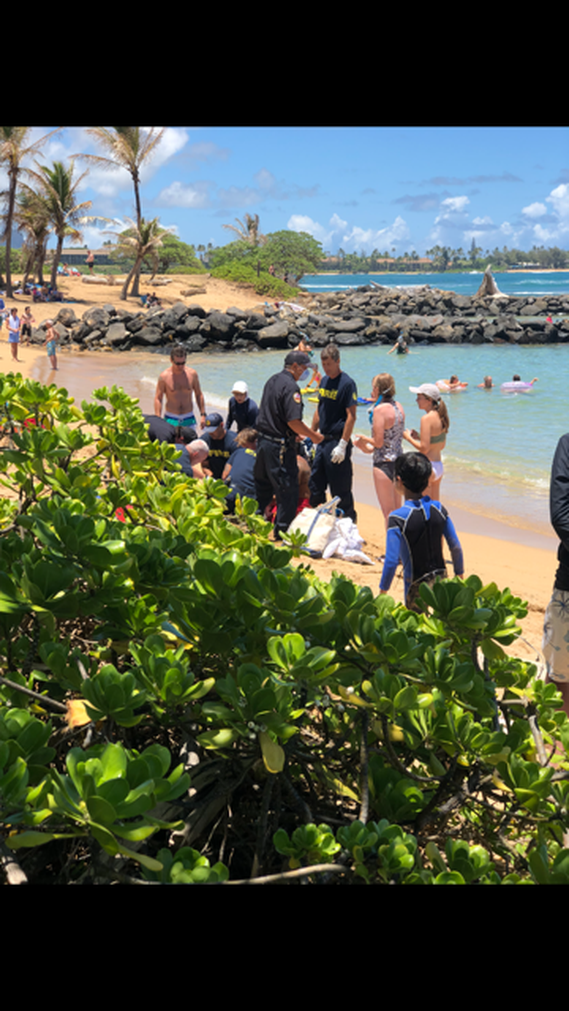 Dr. Nathan Stuempfig of the Kaiser Permanente Modesto hospital, standing at left with green and blue swim trunks, and Dr. Nicole Loeffler-Siu, next to him in white hat, a Modesto native working in Kaiser’s neonatal intensive care unit in Vallejo, monitor parademics’ work after reviving a 58-year-old woman who nearly drowned Aug. 4, 2022 at Lydegate Beach on the Hawaiian island of Kauai.
