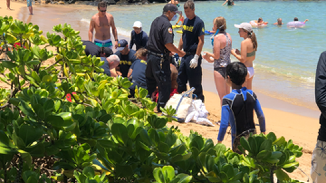 Nathan Stuempfig, a Modesto doctor, stands at left in green and blue swim trunks by Dr. Nicole Loeffler-Siu, a Modesto native in white hat. Both are Kaiser physicians on separate family vacations who helped revive a 58-year-old woman who nearly drowned Aug. 4, 2022 at Lydegate Beach on the Hawaiian island of Kauai.