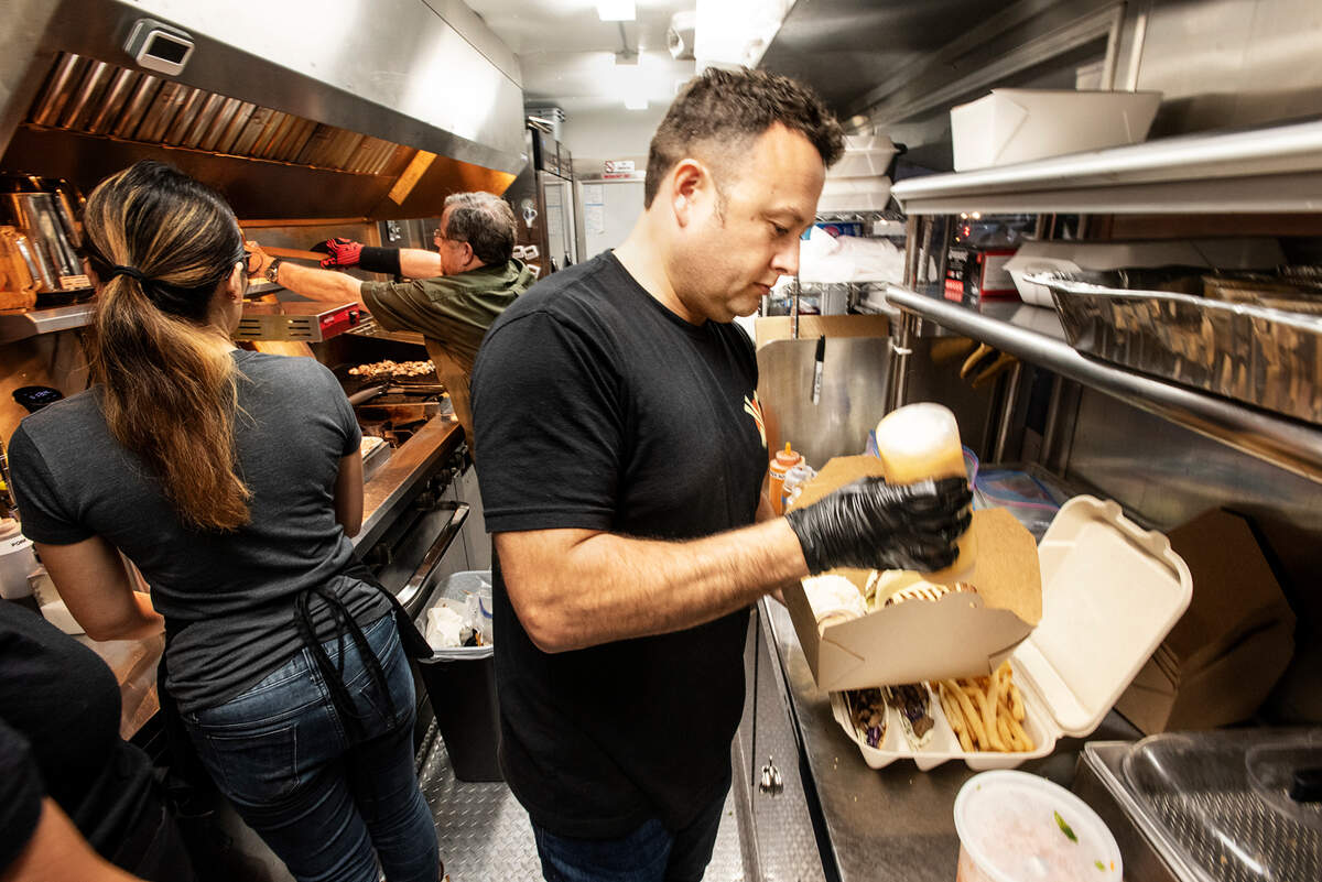 East Meats West owner Justin Hanks, right, prepares a meal inside his Asian and American food truck at Rodin Farm fruit stand on Oakdale Road in Modesto, Calif., Dec. 2, 2021.