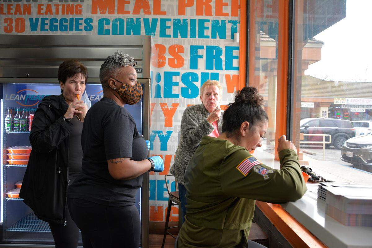 LeanFeast Modesto owner Gia Smith (center) talks with customers inside her new meal prep business Jan. 6, 2022.