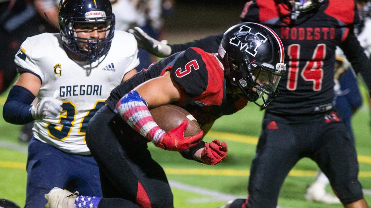 Garrett Bidwell, 5, works his way up field with Elijah Hernandez, 34, of Gregori High closing in. Modesto took on Gregori football at Downey Thursday, Oct. 07, 2021 in a battle that left Modesto with another loss of 15-43.