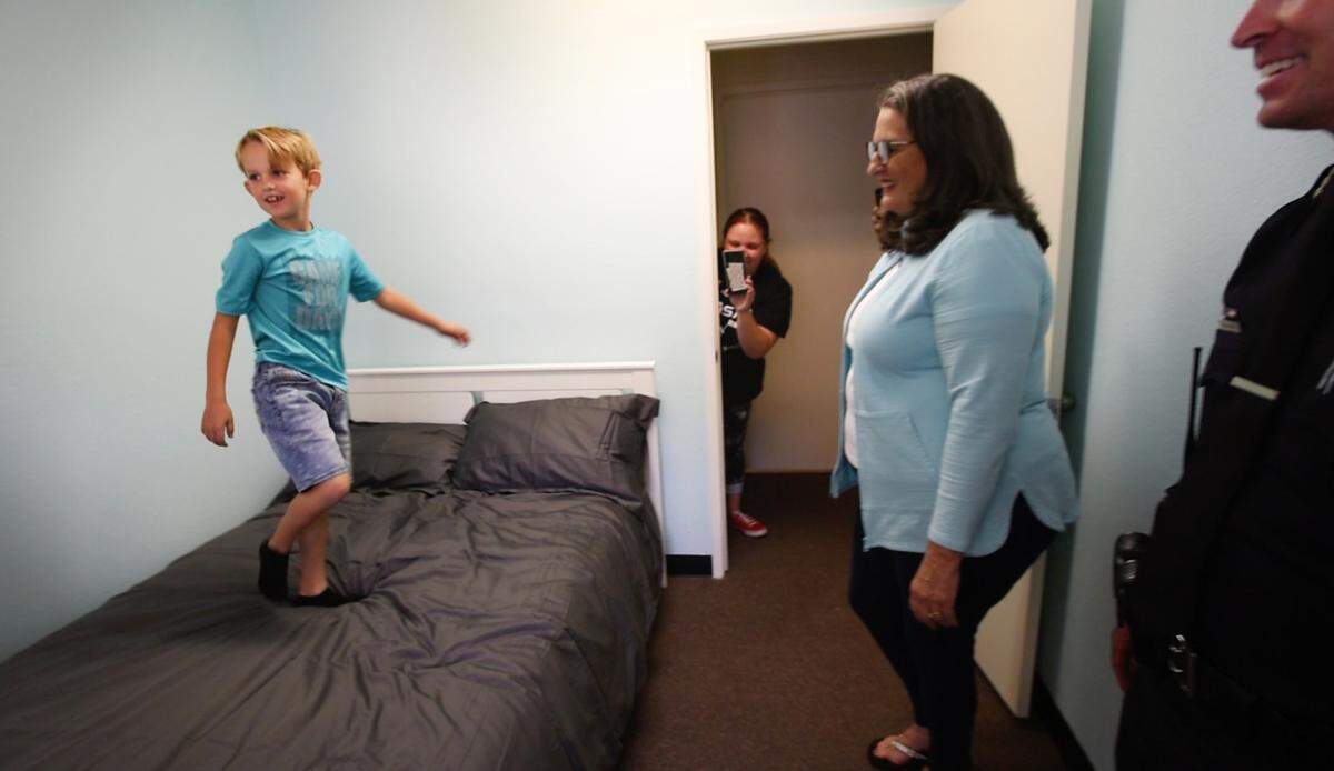 Modesto mayor Sue Zwhalen, and Police Chief Brandon Gillespie watch as Landon Monk, 9, jumps on his new bed in his newly remodeled bedroom in Modesto, Calif., on Friday, June 3, 2022. MPD and other local law enforcement members remodeled six rooms for nine children in Modesto and Empire through 10K with a Cop and the Healthy Room Project.