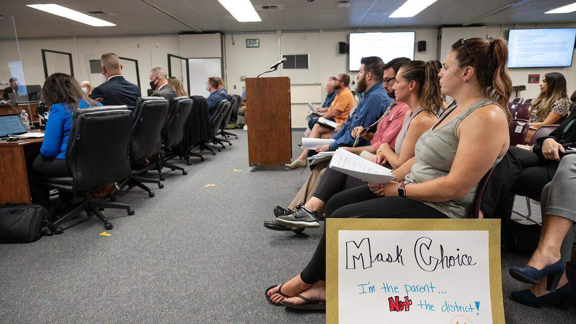 Amanda Stall, right, with sign, and others attend the Modesto City Schools board meeting to advocate for a change in mask policy for the coming school year of in-person learning. Photographed at the Modesto City Schools board meeting in Modesto, Calif., on Monday, July 26, 2021.