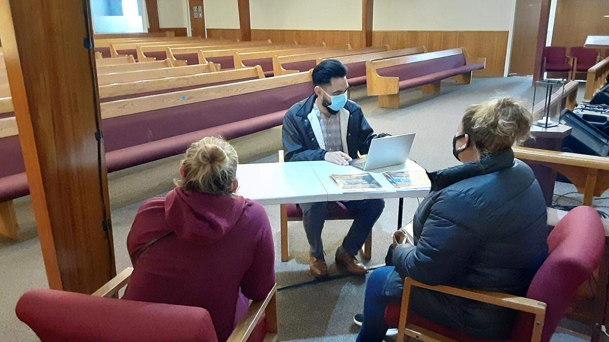 Mobile Outreach Assistance team member Nico Solorio helps two women Monday, March 15, 2021, at The Gathering Covenant Church in Patterson, Calif., in applying for the rental assistance program.