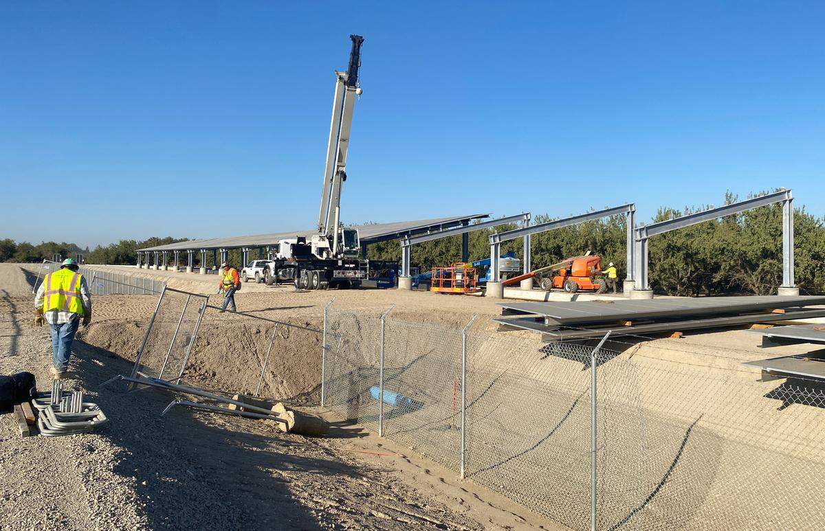 Workers assemble a solar panel array over a Turlock Irrigation District canal in Ceres.