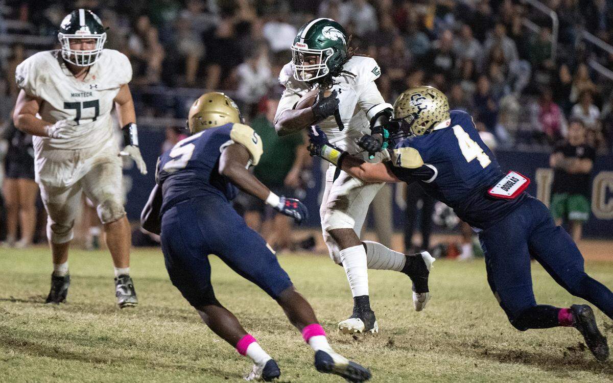 Manteca’s Bryson Davis runs the ball as Central Catholic’s Seth Van Dyk (4) and Carter Meeks close the gap during the Valley Oak League game at Central Catholic High School in Modesto, Calif., Friday, Oct. 20, 2023.