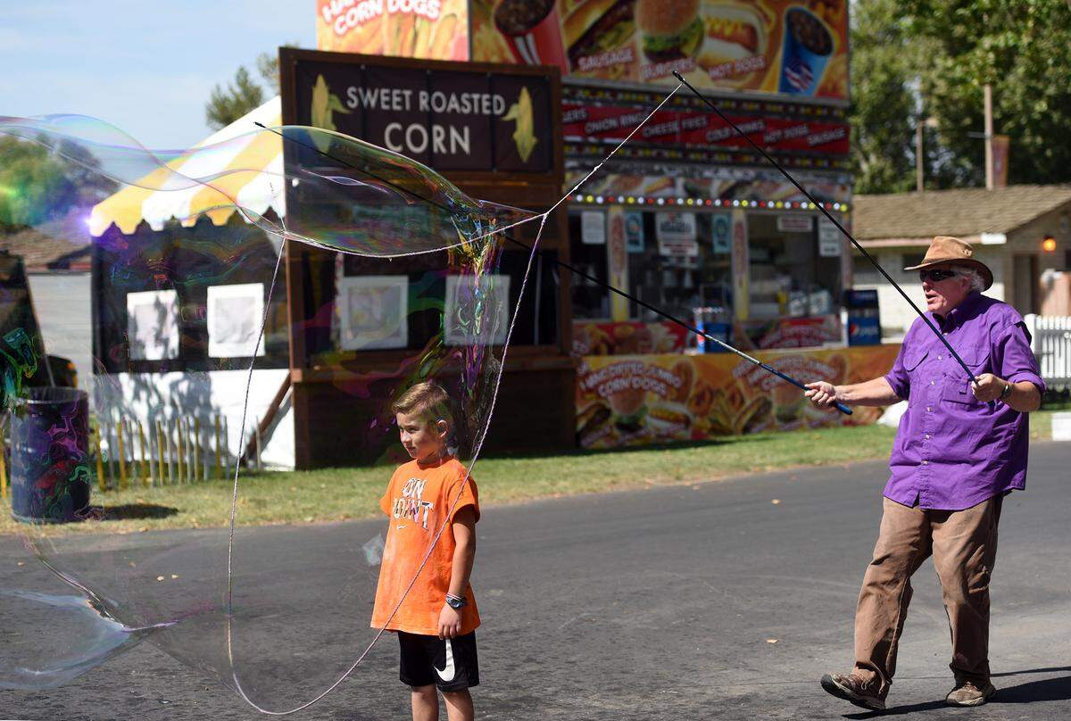 Seven year old Bentley Blevins gets caught up in a bubble with Sterling the Bubblesmith at the Stanislaus County Fair in Turlock, Calif. on Thursday, July 12, 2018. 