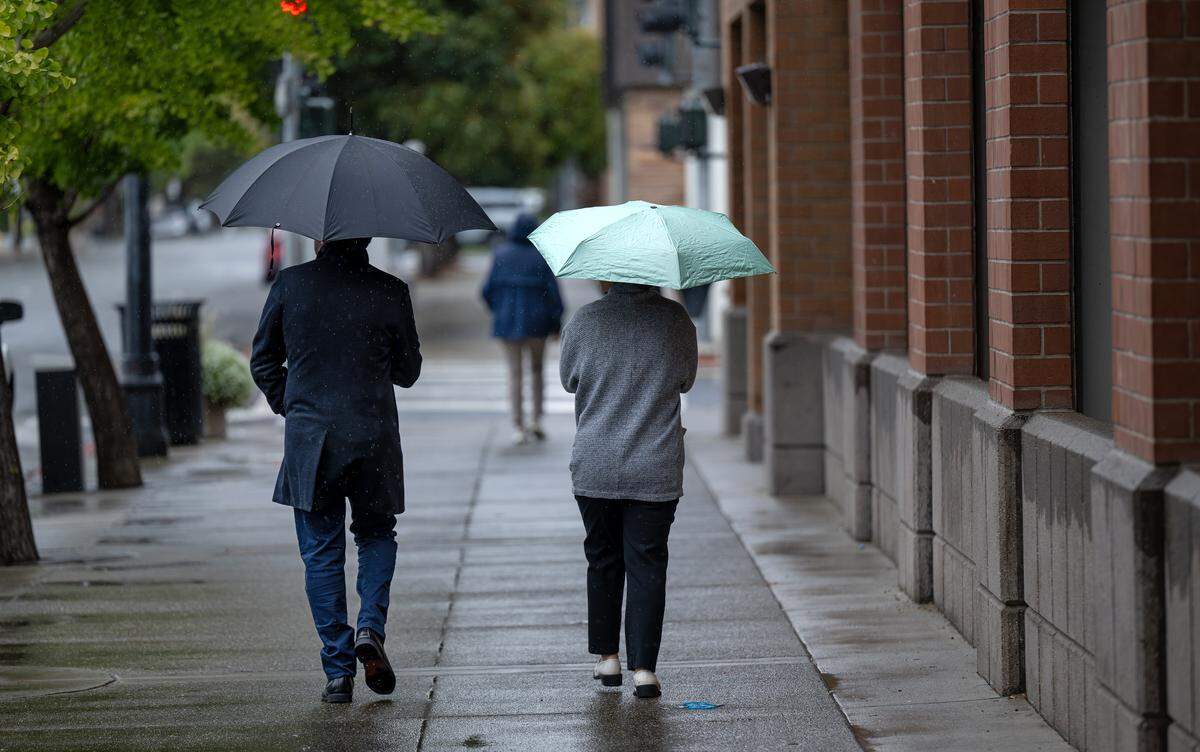 People walk in the light rain on K Street in Modesto Tuesday, Oct. 14, 2025.