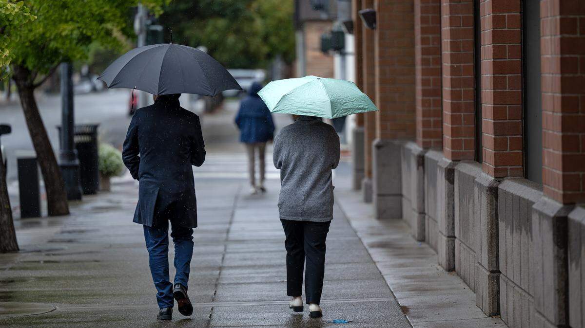 People walk in the light rain on K Street in Modesto onTuesday, Oct. 14, 2025. 