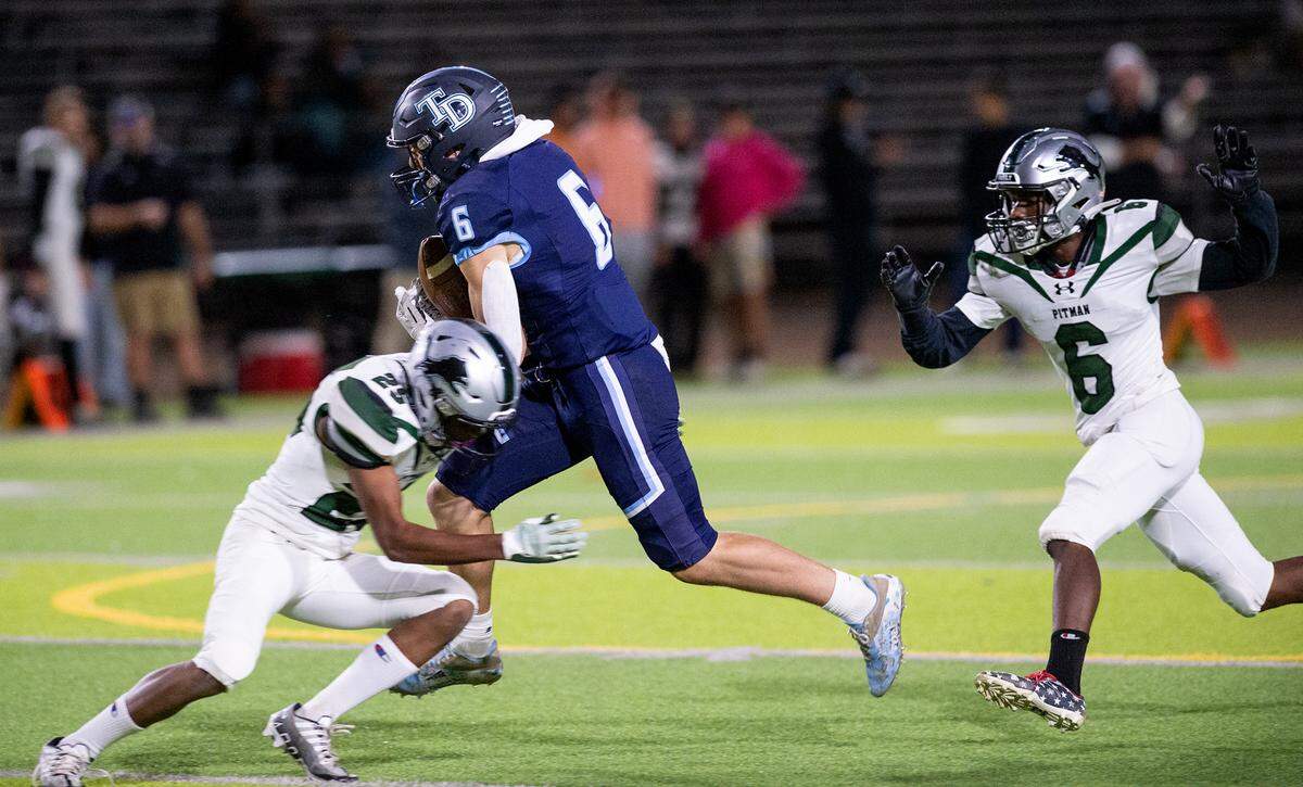 Downey’s Gavin Garcia makes a catch and is stopped by Pitman’s Aric Singh during the Central California Athletic League game at Downey High School in Modesto, Calif., Friday, Oct. 28, 2022.