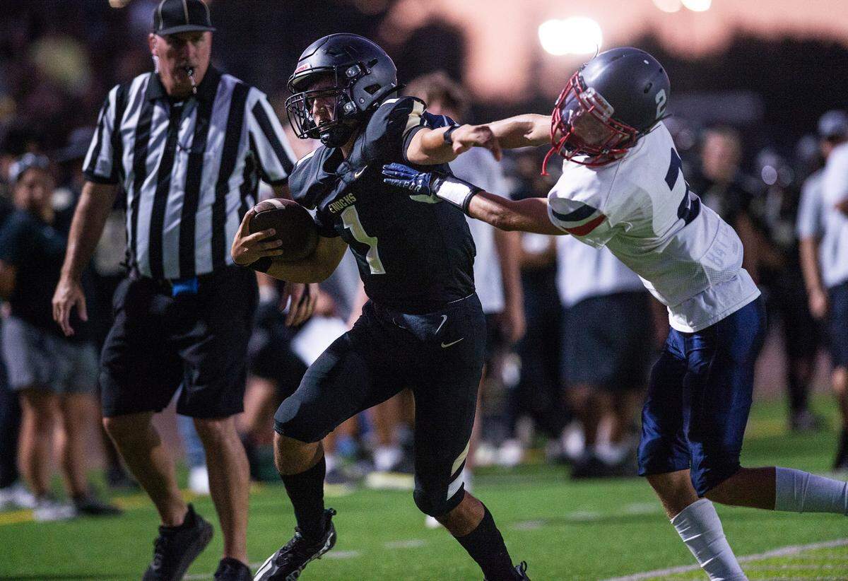 Enochs quarterback Adam Ammar runs the ball as Beyer’s Brock Gross defends during the Sylvan Bowl at Downey High School in Modesto, Calif., on Friday, August 19, 2022.