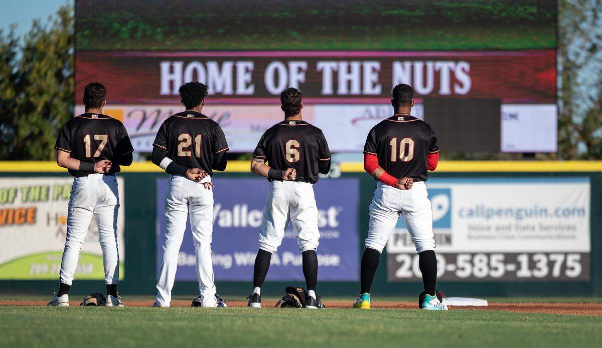 Modesto Nuts fielders stand for the National Anthem before the California League game with the Stockton Ports at John Thurman Field in Modesto, Calif., on Wednesday, July 6, 2022.