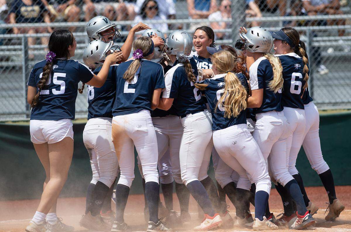 Vista del Lago players mob teammate Morgan Sweet after she hit a three-run home run during the CIF Sac-Joaquin Section Division III softball championship game with Central Catholic at Delta College in Stockton, Calif., on Saturday, May 28, 2022.