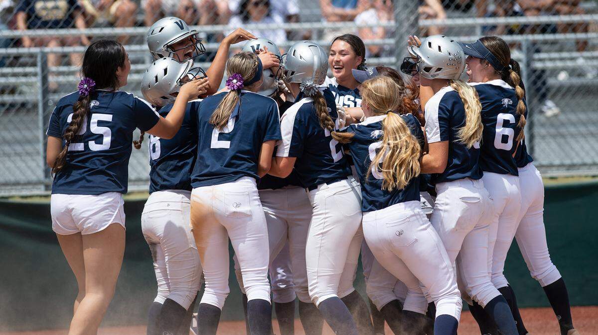 Vista del Lago players mob teammate Morgan Sweet after she hit a three-run home run during the CIF Sac-Joaquin Section Division III softball championship game with Central Catholic at Delta College in Stockton, Calif., on Saturday, May 28, 2022.