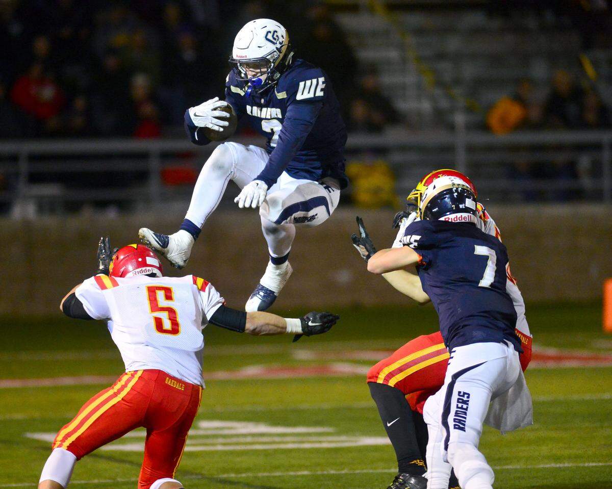 Central Catholic running back Justin Rice leaps over  Oakdale's Lane Tripp (5) during the Division III Championship game between Oakdale and Central Catholic, where Central Catholic won 21-7 at Lincoln High School in Stockton on Dec. 4, 2015.  