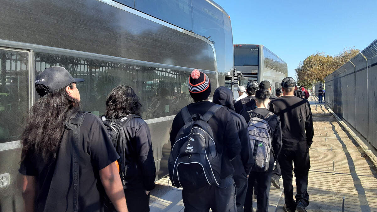 Tesla workers line up waiting for buses to take them to their Bay Area jobs in Modesto, Calif., Thursday, Oct. 27, 2022. The carmaker is leasing 500 parking spaces at the airport and will pay the city $480,000 annually.
