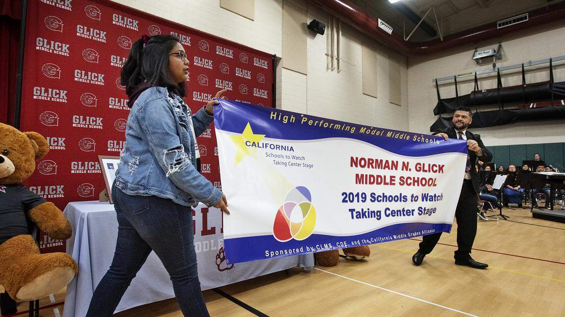 Student body president Elizabeth Romero, left, and principal Isaias Rumayor unveil a California Schools to Watch banner as the students and educators were recognized during a school assembly at Glick Middle School in Modesto, Calif., Thursday, March 28, 2019.