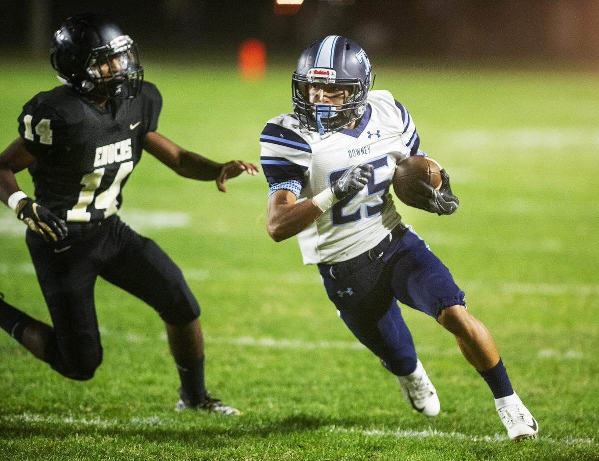 Downey’s Robert Rivera runs the ball as Enochs’ Domnic Prasad defends during the Central California Athletic League game at Johansen High School in Modesto, Calif., Friday, Oct. 11, 2019.