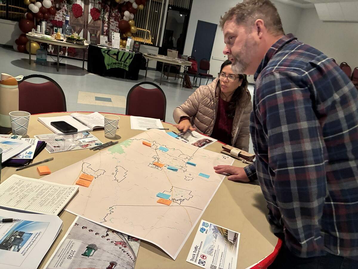 A man leans over a table that has a paper map of the greater Stanislaus County region. Post it notes indicate where residents have found issues like truck idling and other air quality impacts.