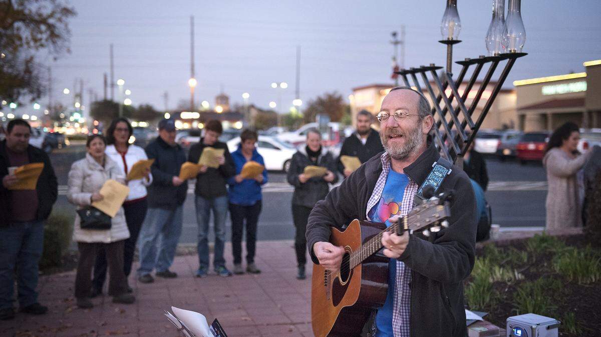 Rabbi Shalom Bochner leads a group in song during the 2017 Hanukkah menorah lighting at McHenry Village in Modesto.