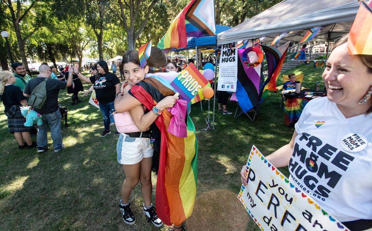 Myranda Ables, 12, gets a hug from Free Mom Hugs organizer Jennifer McQueen, middle, during the MoPride festival at Graceada Park in Modesto, Calif., Saturday, Oct. 1, 2022.