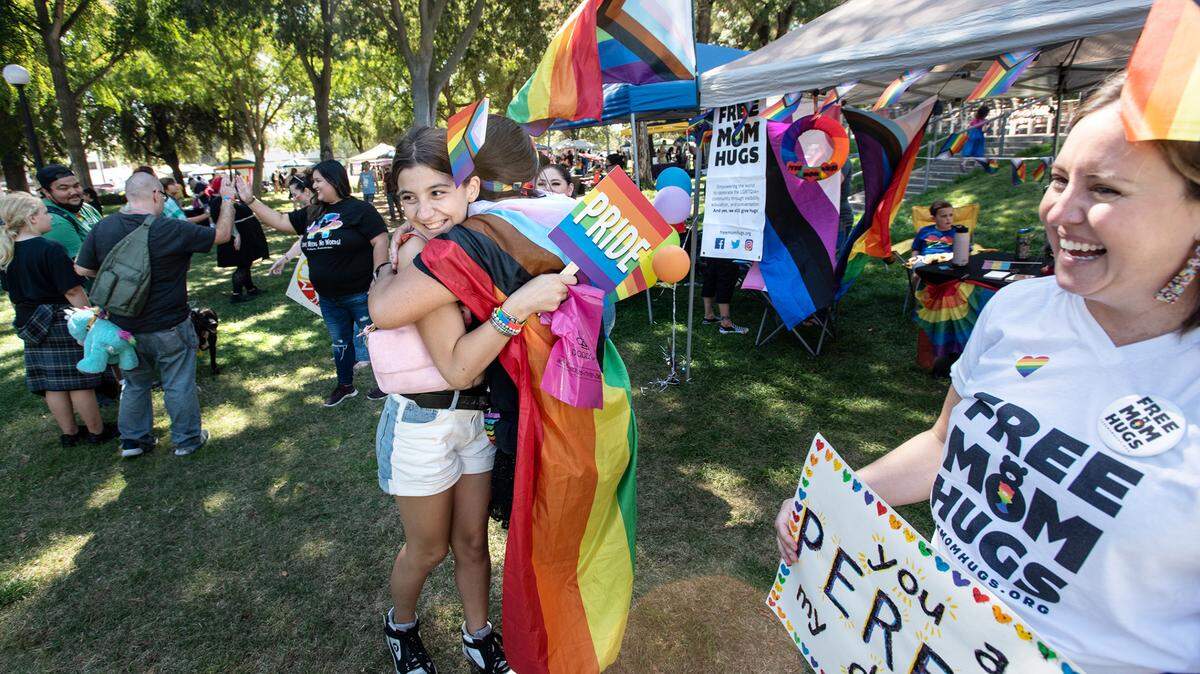 Myranda Ables, 12, gets a hug from Free Mom Hugs organizer Jennifer McQueen, middle, during the MoPride festival at Graceada Park in Modesto, Calif., Saturday, Oct. 1, 2022.