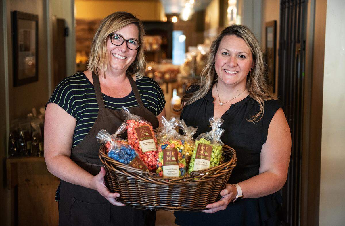 Sisters Stacey Kollmeyer, left, and Kim West, right, owners of the Roberts Ferry Nut Co. hold a basket of flavored popcorn in Oakdale, Calif., on Wendesday, Sept. 16, 2020.