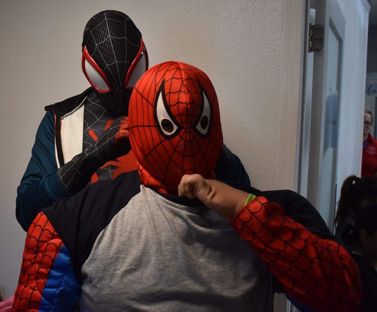 Yuri Williams of Long Beach helps fellow Spider-Man Juan Garcia, 16, put on his mask during a giveaway of clothes, backpacks and school supplies on Sunday, Aug. 11, 2019, at Haven Youth Center on H Street in downtown Modesto.
