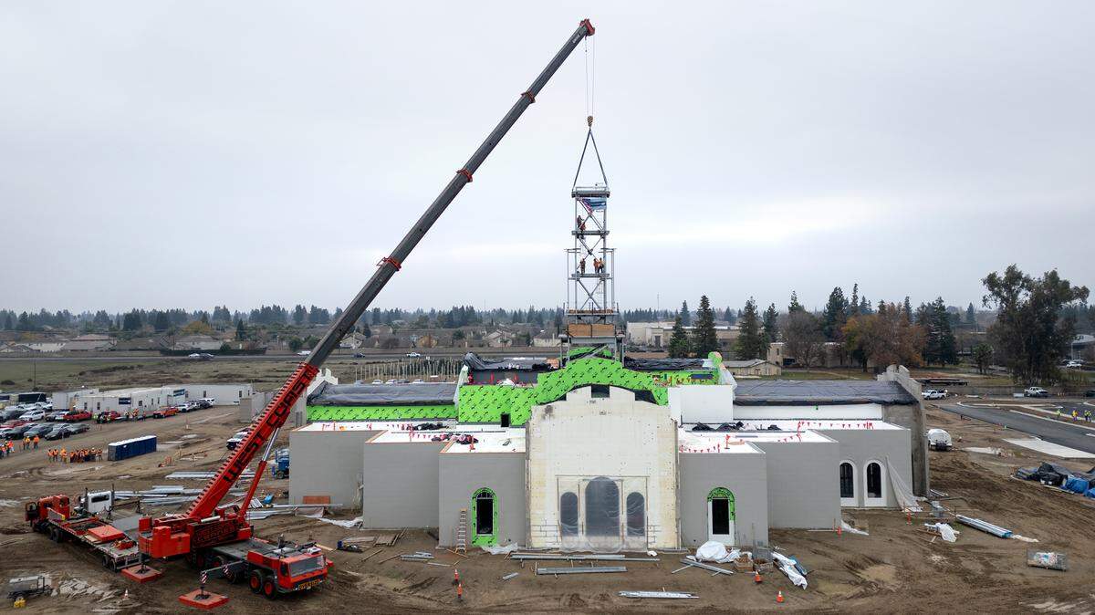 A crew secures the final section of the tower in place at the Church of Jesus Christ of Latter-day Saints’ new temple on Dale Road in Modesto, Thursday, Dec. 19, 2024.