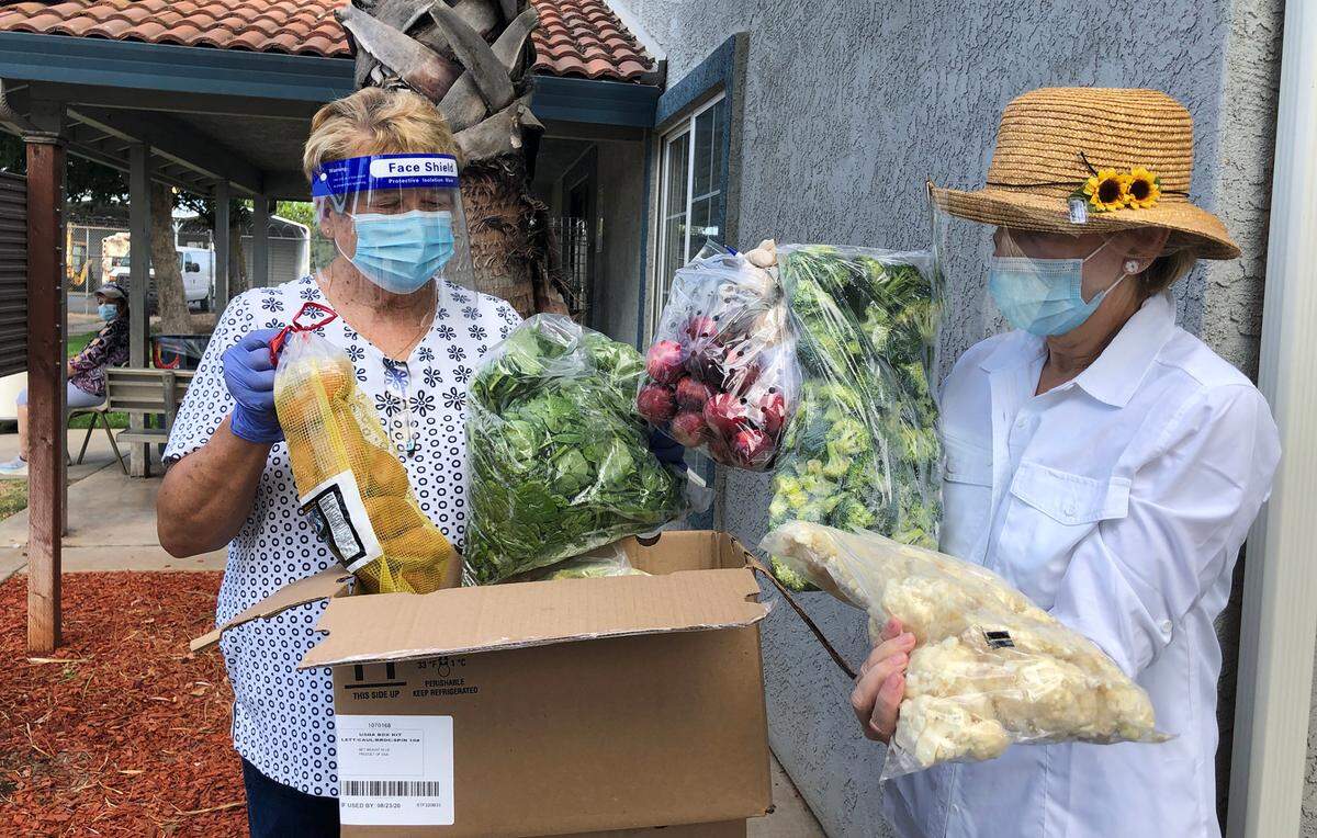 Linda Silva and Betty Bridge, volunteer co-directors of Riverbank Christian Food Sharing, preparing donations for clients at the food bank in August 2020.