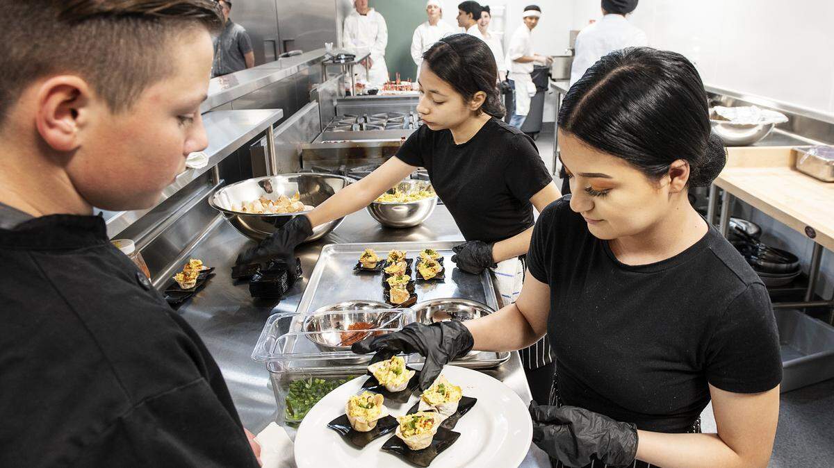 Students Caden Moorhouse, left, Alyssa Ramirez, right, and Evelyn Corona, middle, serve Bombay curry chicken salad appetizers to guests during an open house at the new culinary arts facility at Pitman High School in Turlock, Calif., on Thursday, March. 5, 2020.