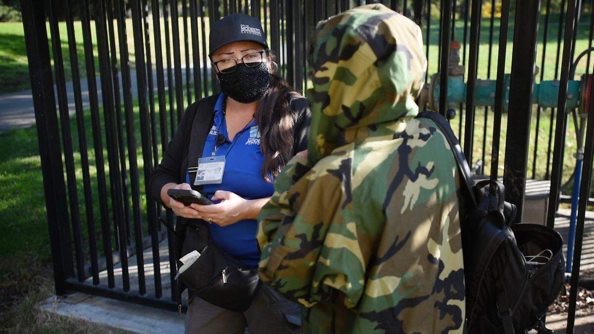 Community Health and Assistance Team outreach specialist Christina Kenney, left, talks with a person who was illegally camping in the restroom at Davis Park in Modesto, Calif., on Wednesday, Nov. 3, 2021.