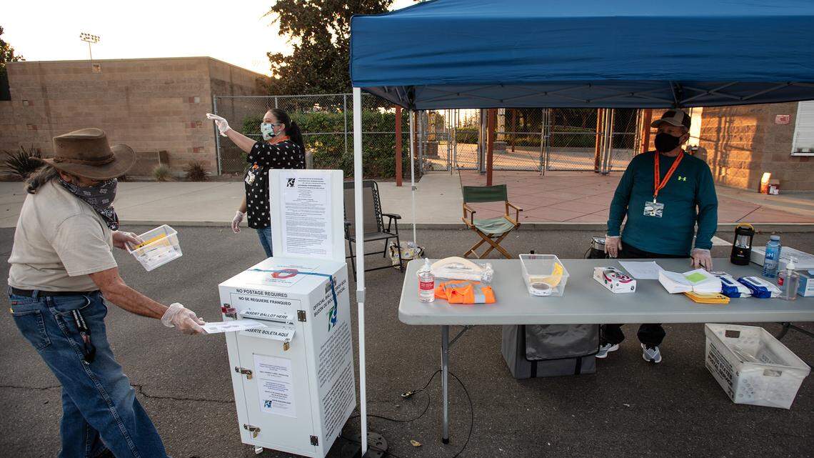 Volunteer poll worker Richard Rodman drops a ballot for a voter at the drive-up ballot drop box at John Thurman Field in Modesto, Calif., on Tuesday, Nov. 3, 2020.