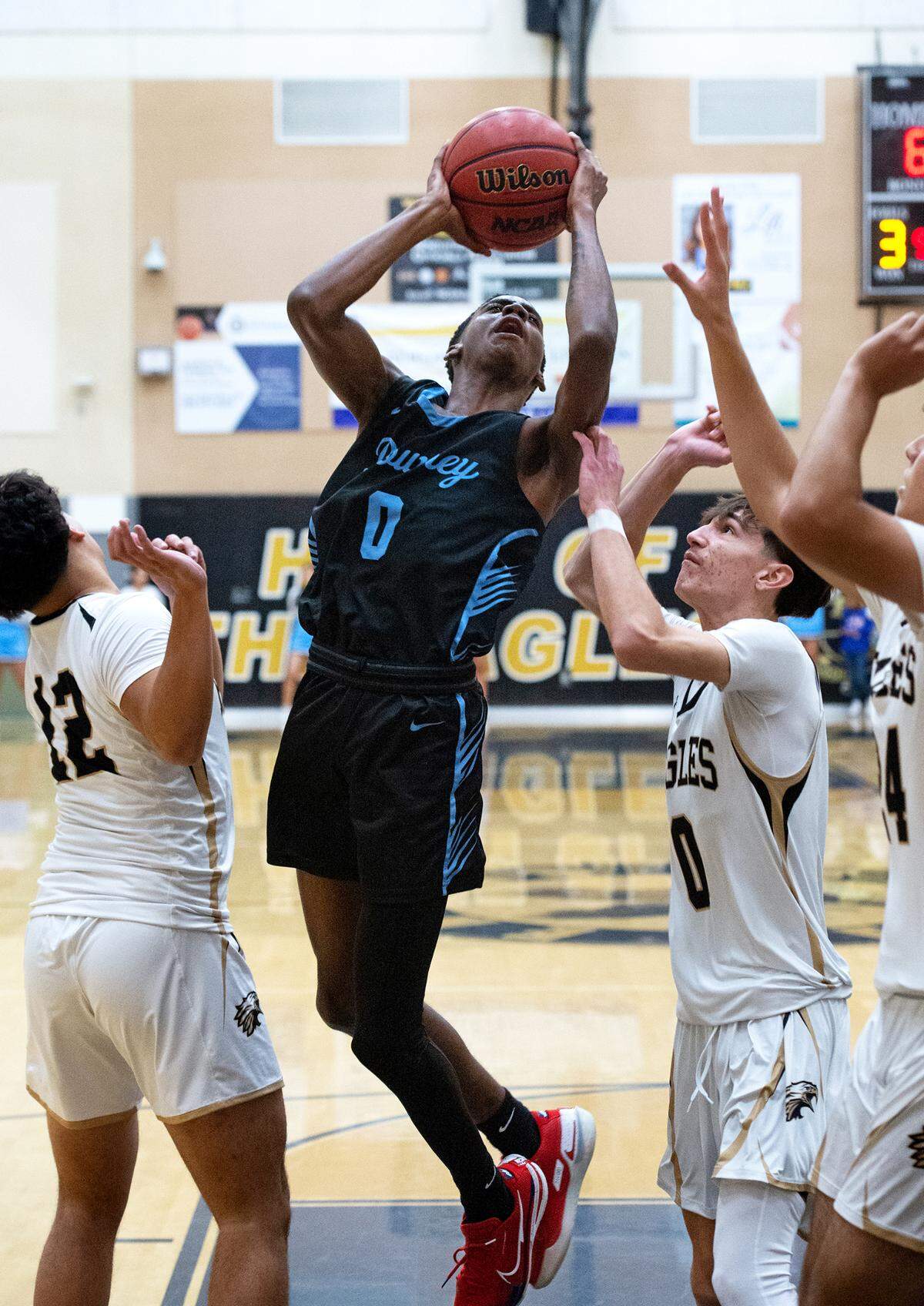Downey’s Reuben Lewis scores past a trio of Enochs defenders during the Central California Athletic League game at Enochs High School in Modesto, Calif., Friday, Jan. 27, 2023.