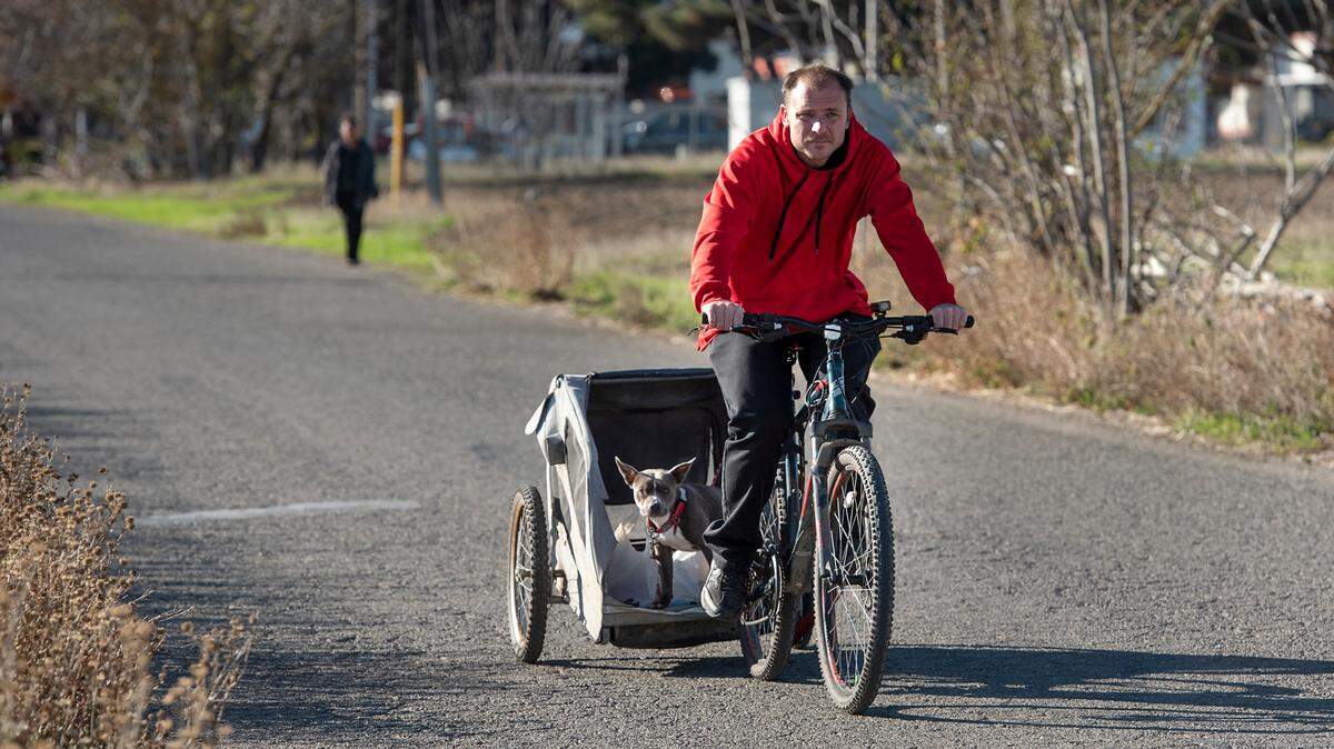 Justin Silva rides back to his RV from downtown with his dog Tyson in Newman, Calif., on Tuesday, Nov. 23, 2021.