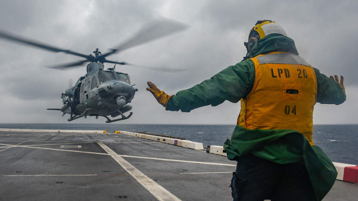 PHILIPPINE SEA (Feb. 17, 2022) Aviation Boatswain’s Mate 2nd Class John Montano, from Oakdale, Calif., assigned to the amphibious transport dock ship USS Green Bay (LPD 20), signals a UH-1Y Huey helicopter from Marine Medium TIltrotor Squadron (VMM) 265 to take off from the flight deck.