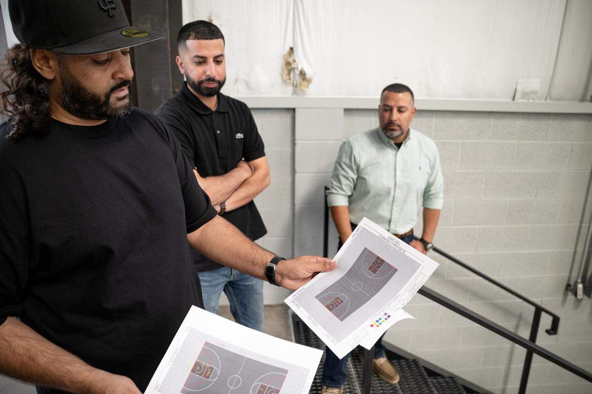 Ginn Sanghera, left, shows how courts will be marked for multiple indoor sports including basketball and volleyball at the Modesto Sports Center in Modesto, Wednesday, June 4, 2025.