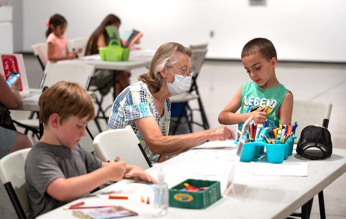 Peggy Hoyle, middle, talks with Charlie Jones, 6, right, as he makes a drawing during the Carnegie Arts Center 10th anniversary block party in Turlock, Calif., on Saturday, June 25, 2022.