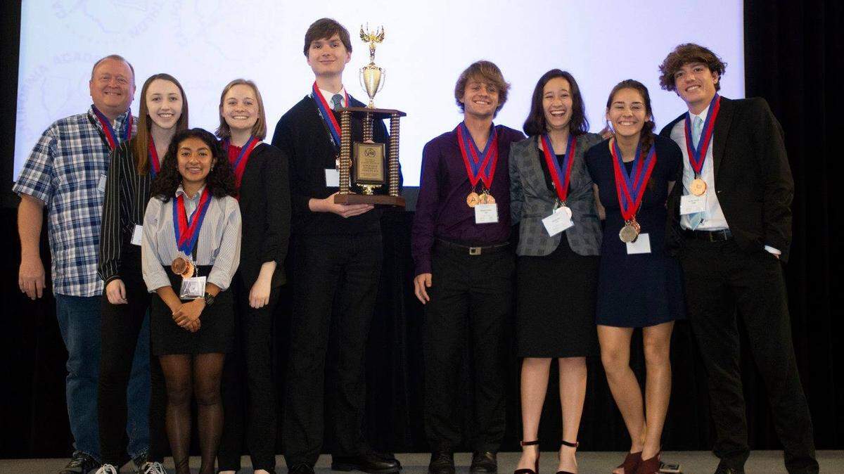 The Hughson High School Academic Decathlon team holds its Super Quiz third-place trophy at the California competition in Sacramento, held March 22-24.
