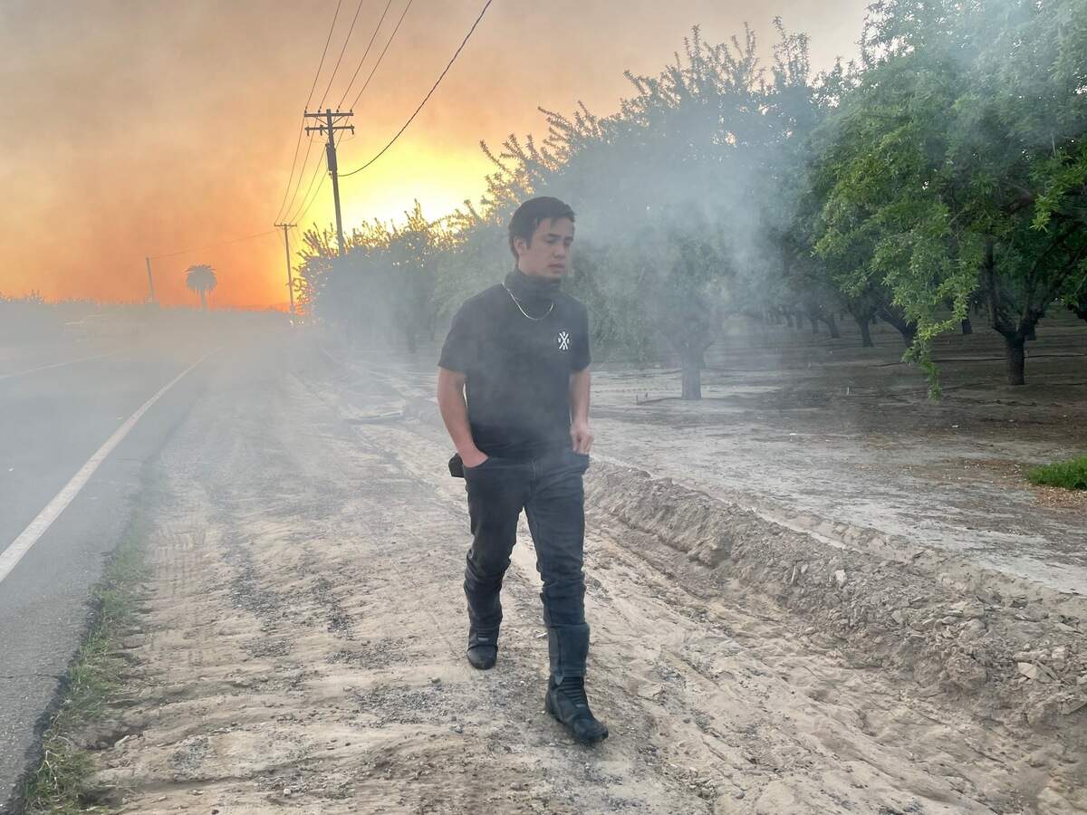 Alex Samson walks out of the smoke following a memorial burnout, in which a truck spun its wheels to create smoke to honor the life of William Shawn Pizarro. Pizarro died in a car crash Sunday March 28, 2021, and Samson said burnouts are often a way to honor the life of a “car person” such as Pizarro.