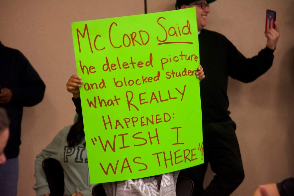 A child holds up a sign with allegations against Patterson Mayor and math teacher Dennis McCord on Dec. 7, 2021, during the Patterson Joint Unified School District school board meeting. McCord is accused of having inappropriate contact with a student on Snapchat.