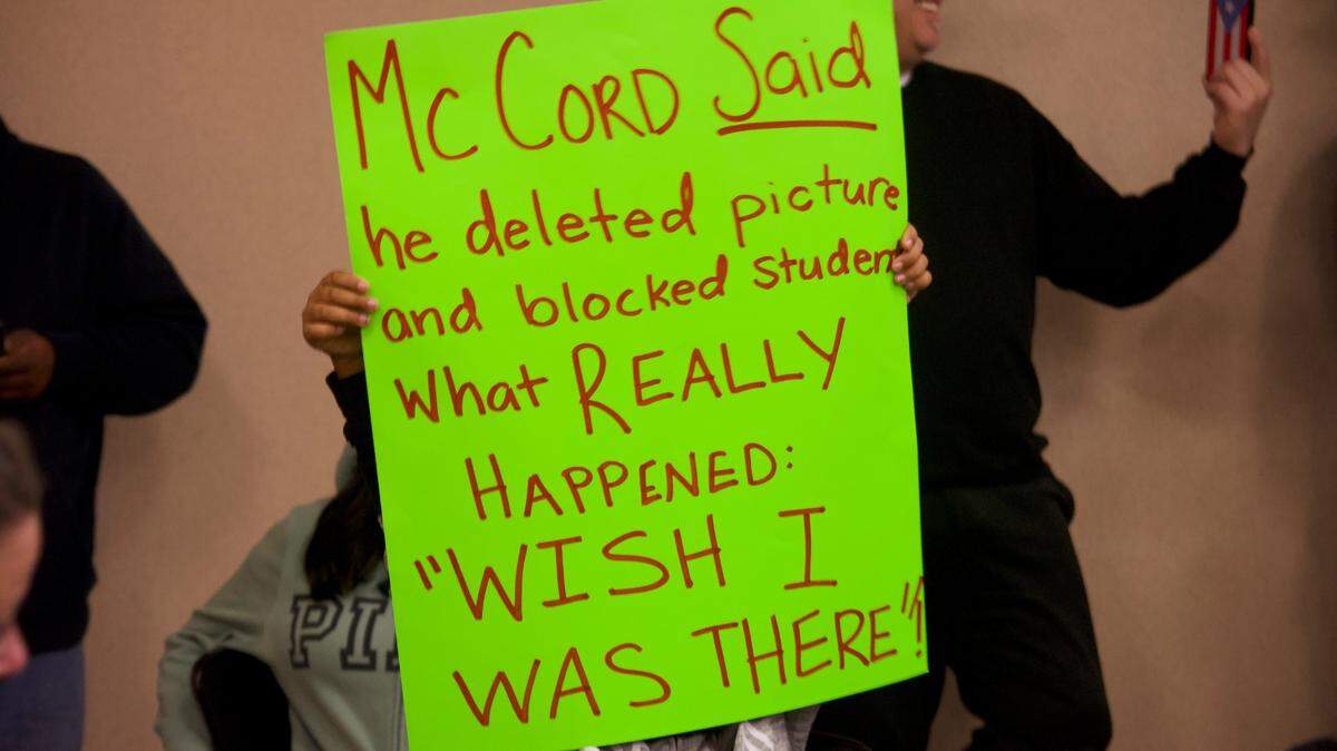 A child holds up a sign with allegations against Patterson Mayor and math teacher Dennis McCord on Dec. 7, 2021, during the Patterson Joint Unified School District school board meeting. McCord is accused of having inappropriate contact with a student on Snapchat.