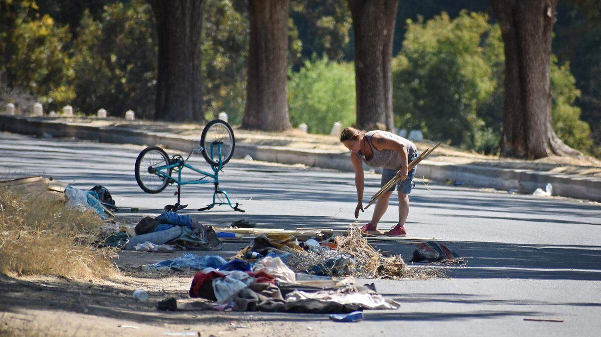 Gwenda Campbell, who’s staying in the Mary Grogan Grove area of Legion Park in Modesto, picks wood out of rubbish along Legion Drive on Tuesday, Aug. 28, 2018.